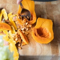 a spoon scooping out the seeds form inside the squash