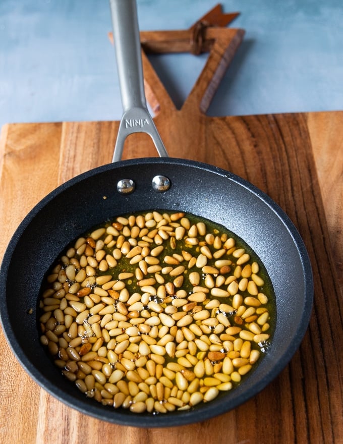 the skillet with the toasted golden pine nuts in olive oil 