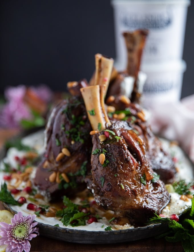 lamb shanks are placed over the skyr sauce and hen garnished with parsley, pine nuts and pomegranate arils 