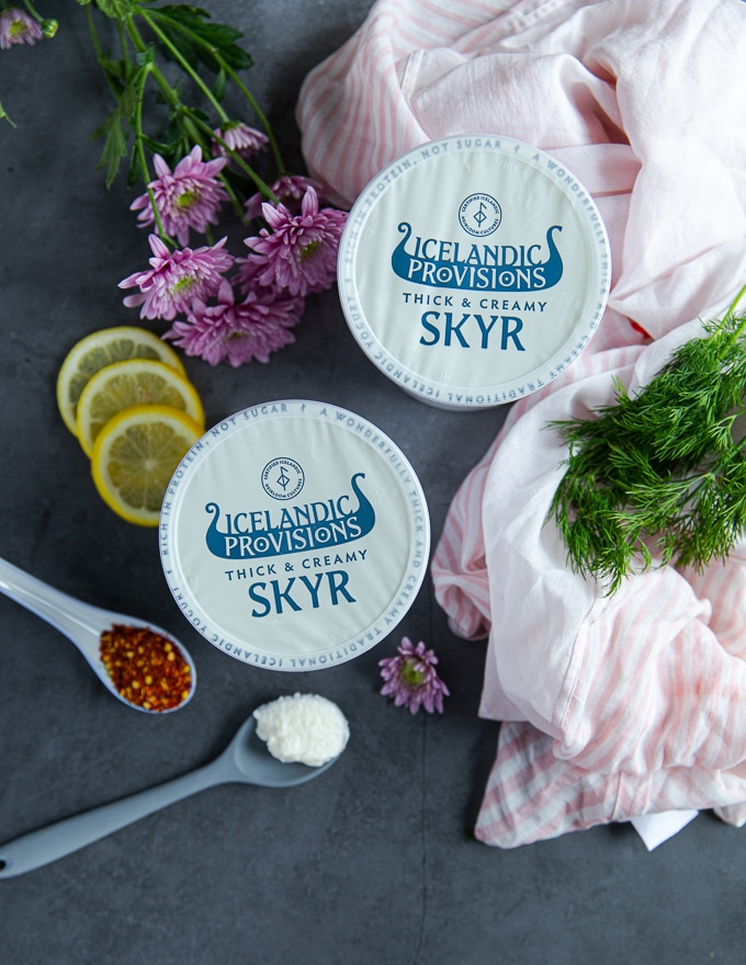 two boxes of icelandic provisions skyr surrounded by lemon slices, seasoning and fresh dill