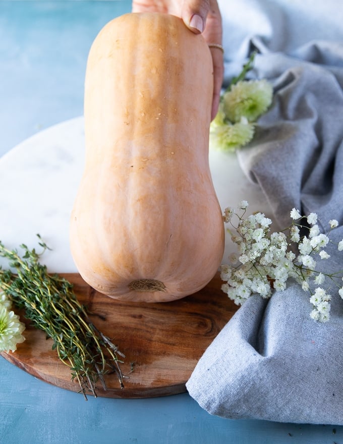 A whole butternut squash over a cutting board