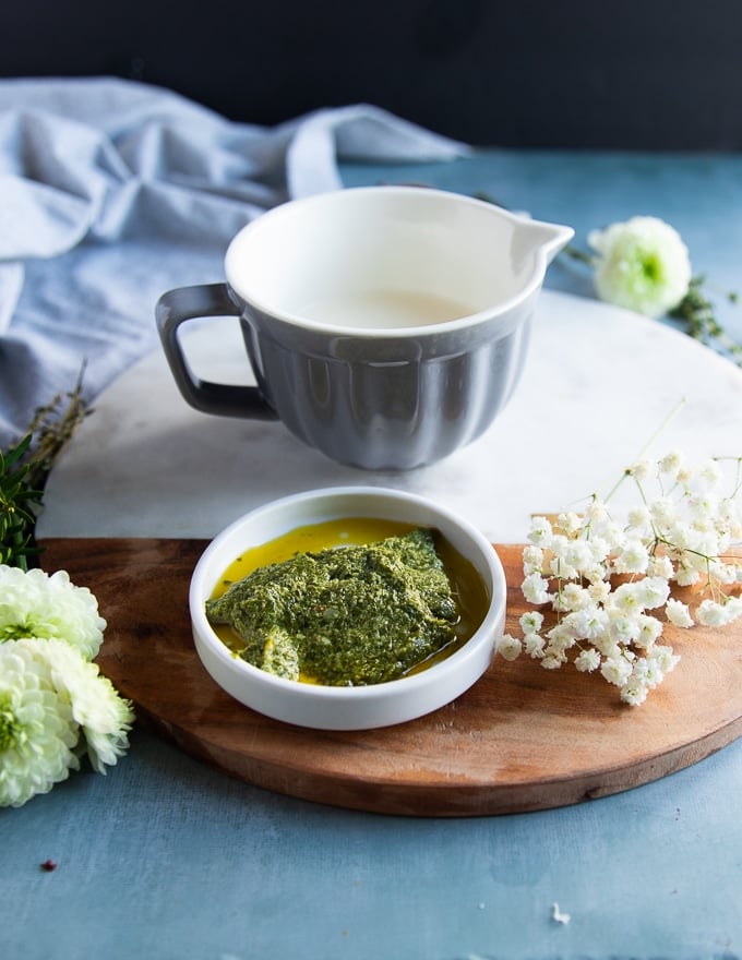 a cup of cream and a plate of homemade basil pesto to make the casserole sauce and topping