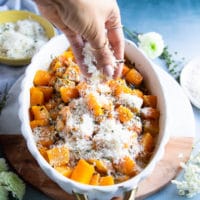 A hand sprinkling the casserole topping over the butternut squash recipe