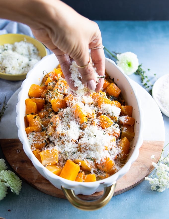 A hand sprinkling the casserole topping over the butternut squash recipe