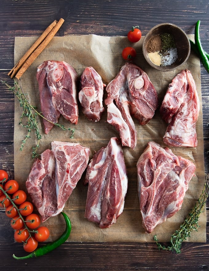 Raw lamb shoulder chops on parchment paper showing the cut of the shoulder and the thickness of the meat 