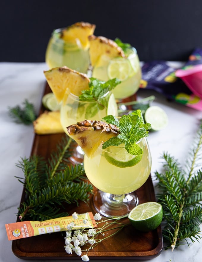 pineapple mojitos in cups with mint and fresh pineapple garnishes