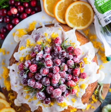 Orange cake with cranberries served with sugared cranberries over the top and surrounded by orange slices