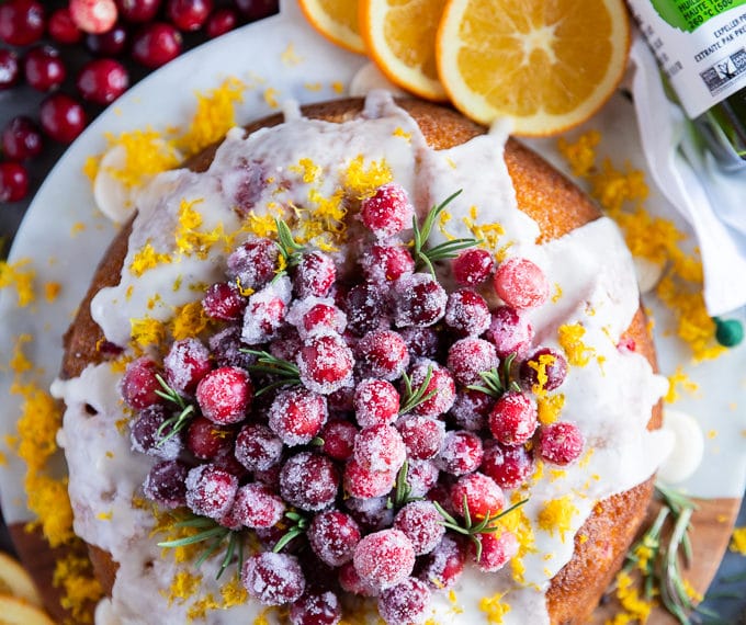 Orange cake with cranberries served with sugared cranberries over the top and surrounded by orange slices
