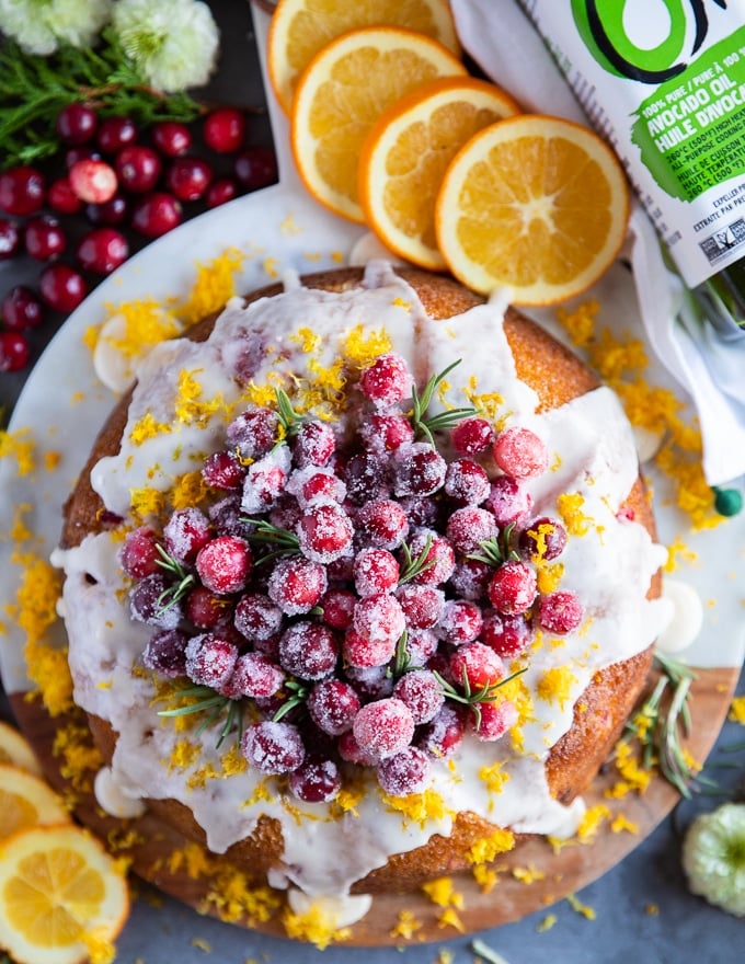 Orange cake with cranberries served with sugared cranberries over the top and surrounded by orange slices