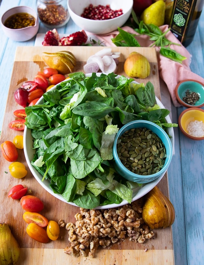 ingredients for the simple salad includes greens, fresh pears, tomatoes, nuts, seeds, shallots and fresh herbs