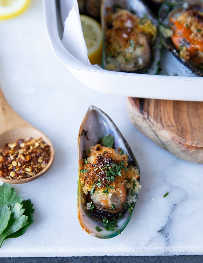 A fully cooked single green mussel on a marble close up to show the final recipe