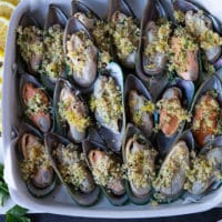 new zealand mussels or green mussels in a single layer on a baking sheet topped with the panko mixture and ready to go in the oven