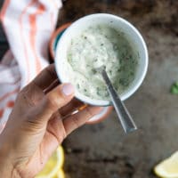 a hand holding the ready garlic mixture to flavor the lobster tail