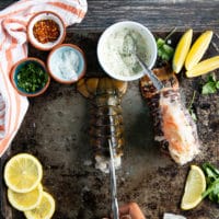 A hand holding a scissors cutting through the center of the lobster tail