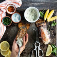 A hand spooning in the garlic sauce to infuse the lobster trail meat in between the shells and over the shell