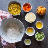 Ingredients for the cormbread recipe including flour, baking powder, cornmeal, grated cheese, eggs, fres corn, oil, grated carrots and zucchini