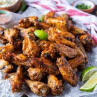 close up of air fryer chicken wings on a platter surrounded by lemon wedges