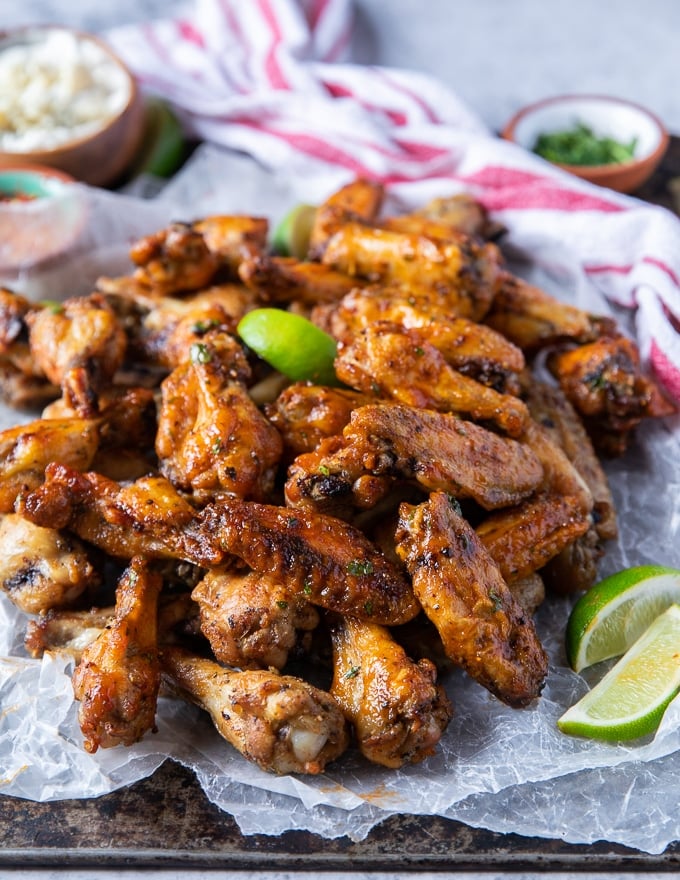 close up of air fryer chicken wings on a platter surrounded by lemon wedges