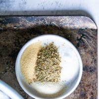 A plate of seasoning including salt, pepper, onion powder, garlic powder and oregano spices