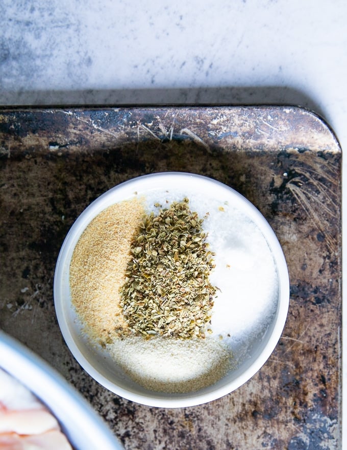 A plate of seasoning including salt, pepper, onion powder, garlic powder and oregano spices