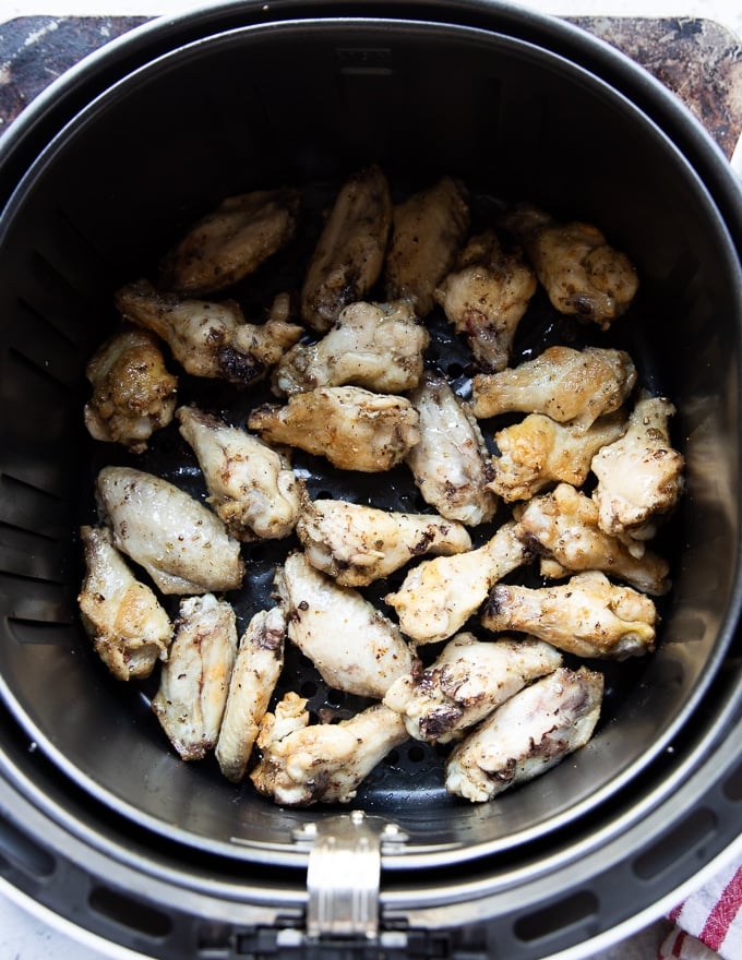 Chicken wings spread in a single layer in an air fryer basket