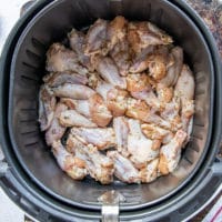 Single layer of chicken wings squeezed tight in an air fryer basket but not overlapped