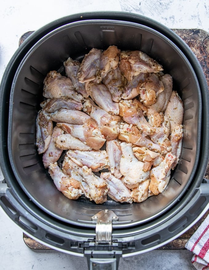 Single layer of chicken wings squeezed tight in an air fryer basket but not overlapped