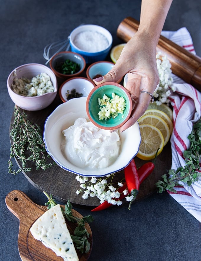 A hand holding a bowl of fresh garlic