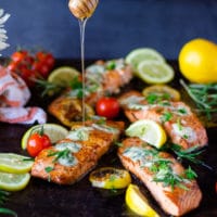 pan seared salmon with blue cheese and a hand drizzling honey on a tray.