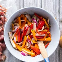 Fajita veggies added to a bowl with some of the marinade