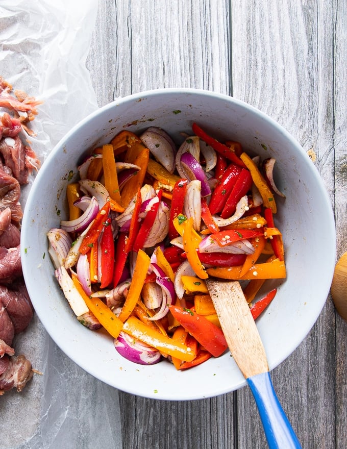 Fajita veggies added to a bowl with some of the marinade 