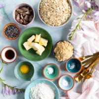 ingredients for oatmeal cookies including butter, oats, sugars, egg, chocolate chips and chunks, flour, salt, baking soda