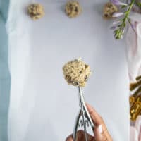 a hand using an ice cream scoop to scoop pieces of cookie dough