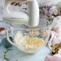 a hand mixer beating up the butter and sugar in a glass bowl to make oatmeal cookies