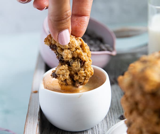 a hand dipping the oatmeal cookie recipe into a cup of espresso