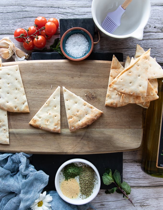 two pita wedges (pita chips) perfectly sliced on a cutting board