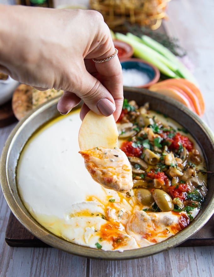 an apple being dipped in the whipped feta