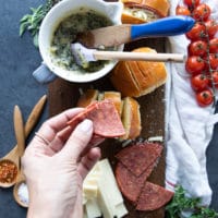 A hand holding a salami piece and ready to stuff it inside the air fryer pizza rolls