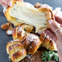 two hands puling apart a pizza roll showing the stretchy cheese