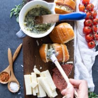 a hand brushing the bread with the garlic butter