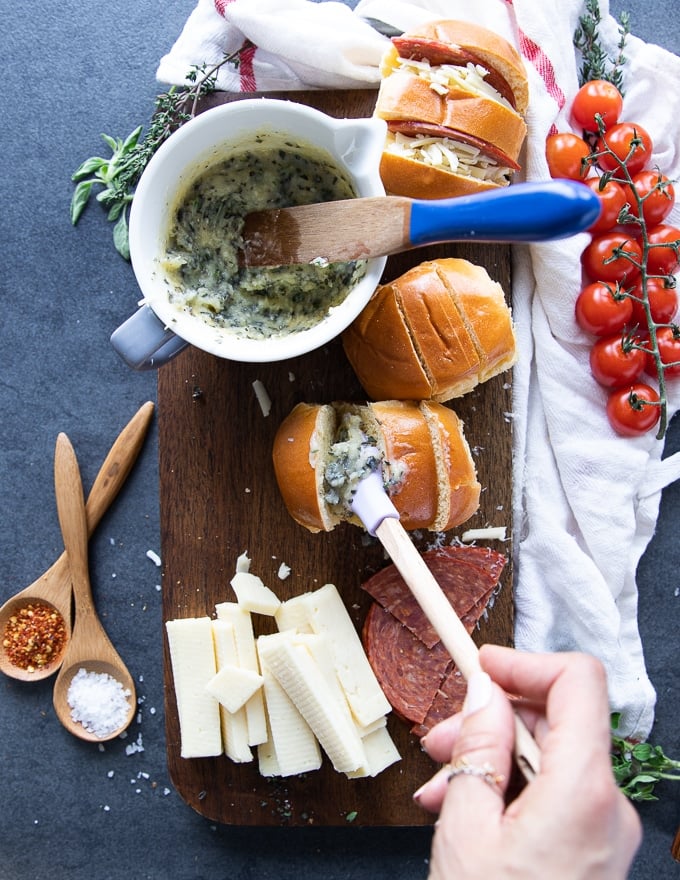 a hand brushing the bread with the garlic butter 