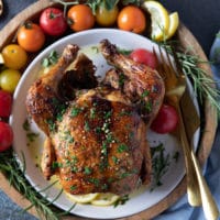 Air fryer whole chicken served on a plate with some parsley on top with crispy skin and perfectly cooked