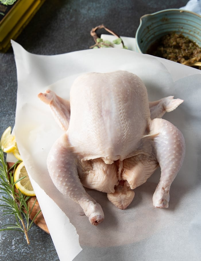 A whole chicken on parchment paper on a cutting board