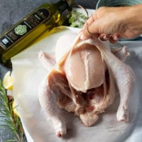 A hand separating the skin from the meat for a whole chicken to make sure it infuses with most flavor during air frying