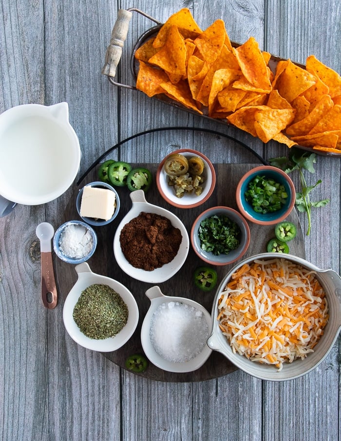 ingredients for the nacho cheese recipe including flour, butter, milk, cheese, spices oregano, chilli powder, cilantro, jalapeno and salt