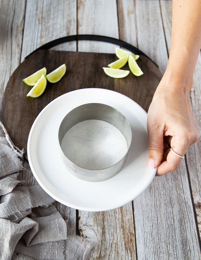 a hand holding a circular mold on a plate