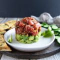 Tuna tartare on a plate layers of marinated tuna chunks and avocado on a plate.