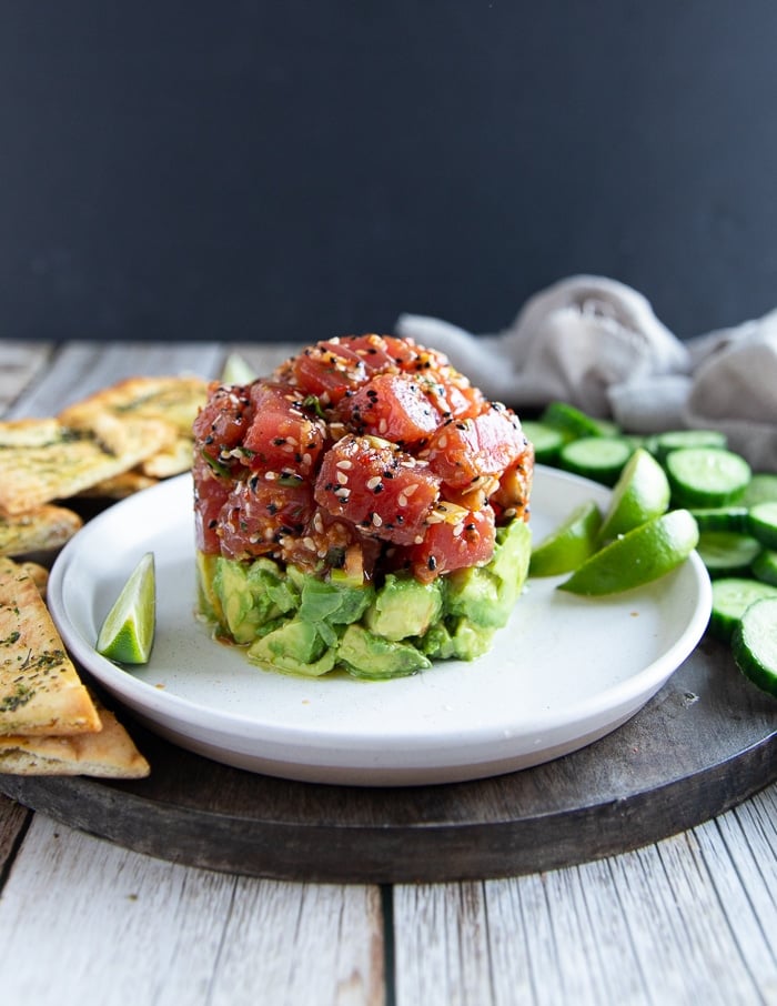 Tuna tartare on a plate layers of marinated tuna chunks and avocado on a plate.