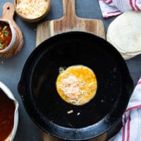 the dipped tortilla in a pan with cheese placed on one half of it