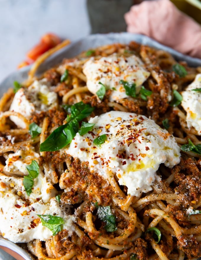 close up of the burrata cheese placed over the pasta and slightly warmed up and seeping into pasta